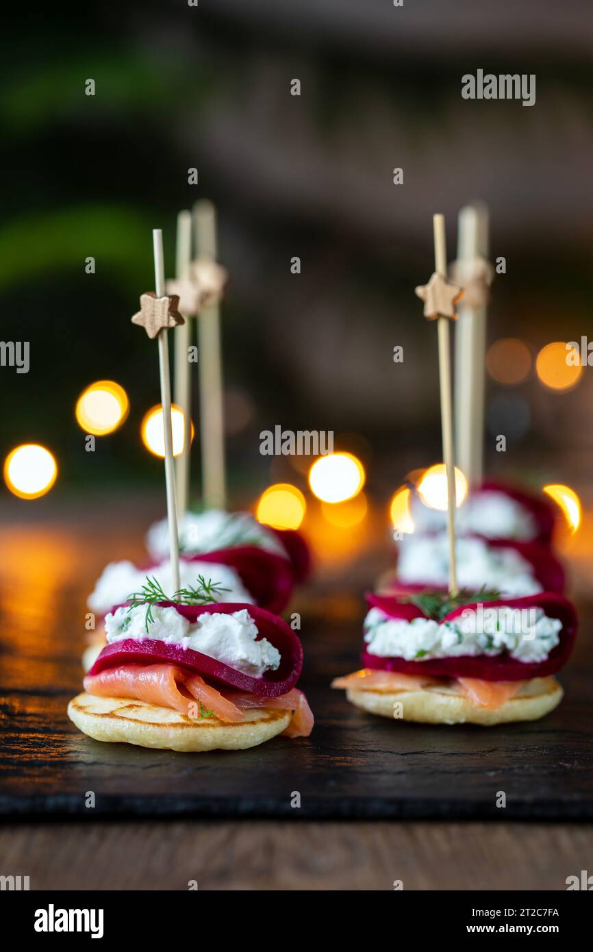 Christmas canapes with blinis with salmon, pickled beetroot and goat cheese Stock Photo