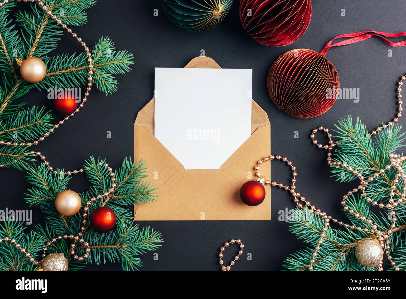 Envelope with blank card and fir branches with Christmas balls on black ...