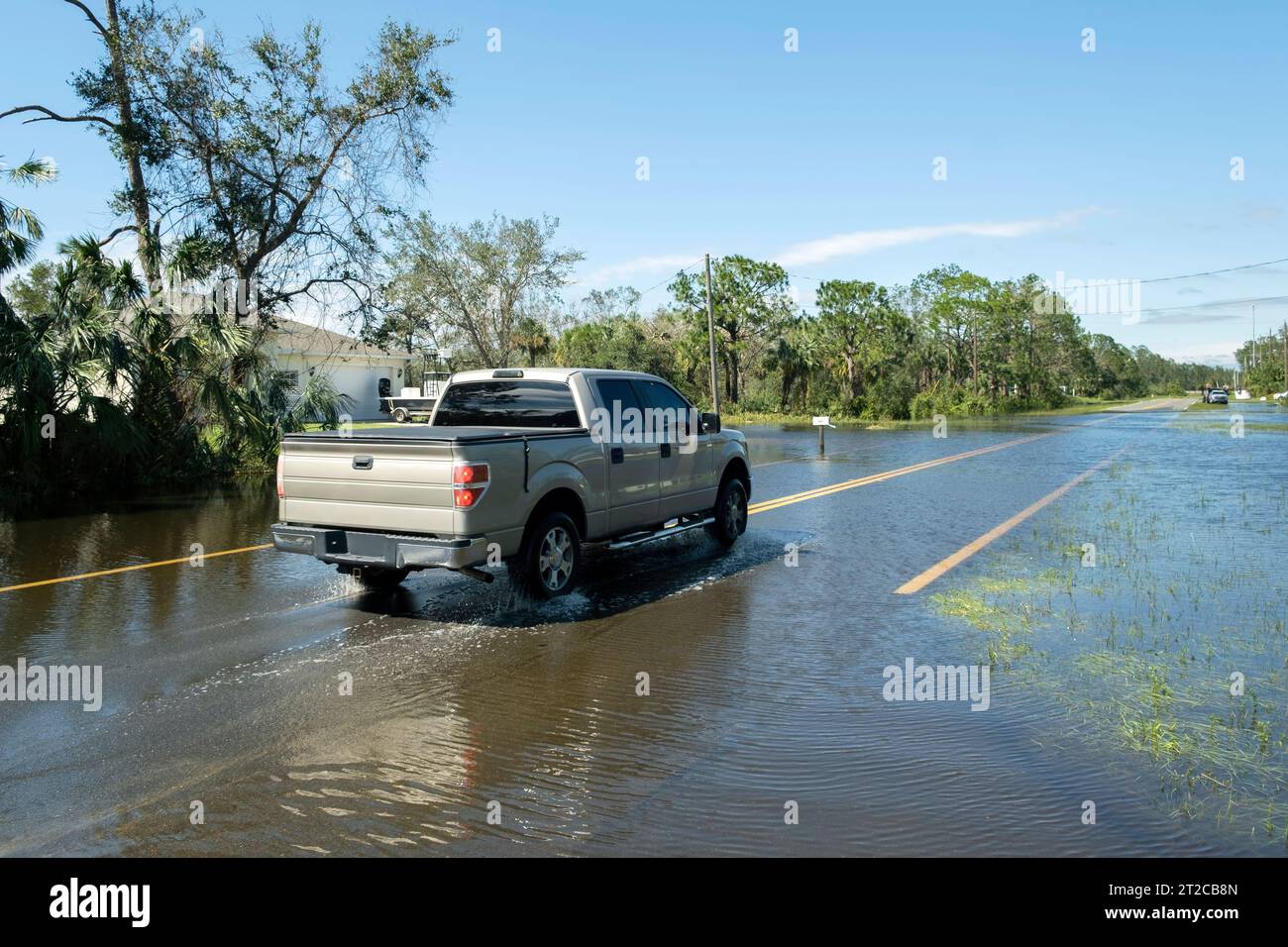 Flooded town street with moving cars submerged under water in Florida ...