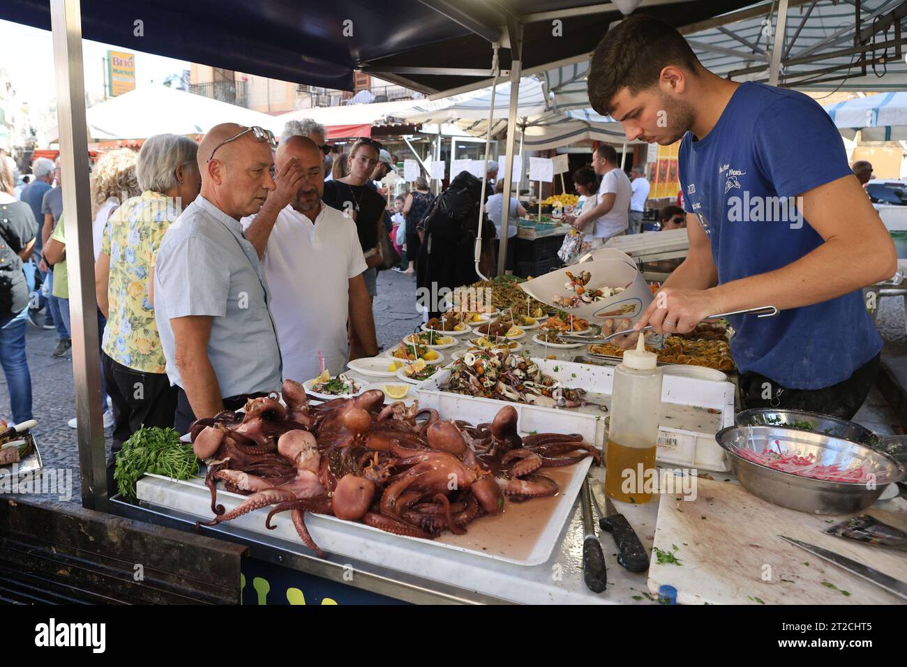 Vendor serving customers plates of seafood in the Ballarò market in Palermo, Sicily, Italy Stock Photo
