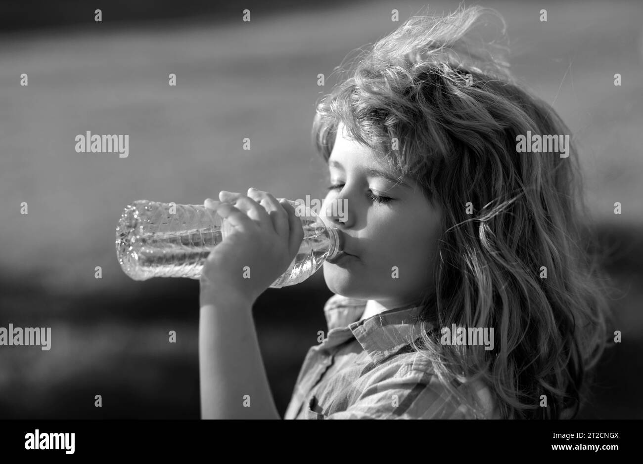Close up portrait of kid drinking water from pet bottle outdoor. Stock Photo