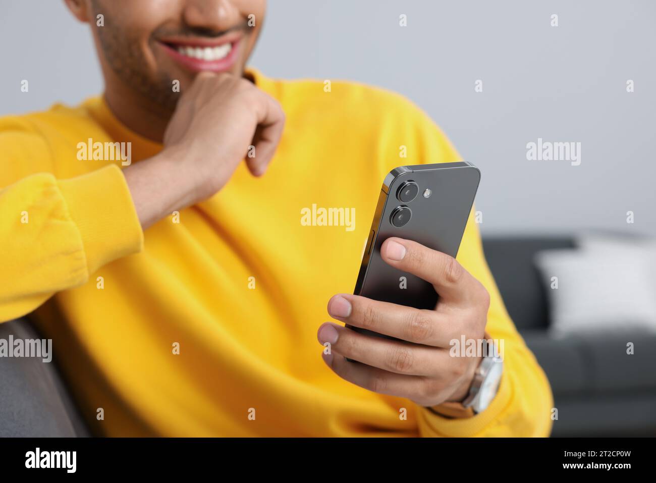 Man sending message via smartphone indoors, closeup Stock Photo