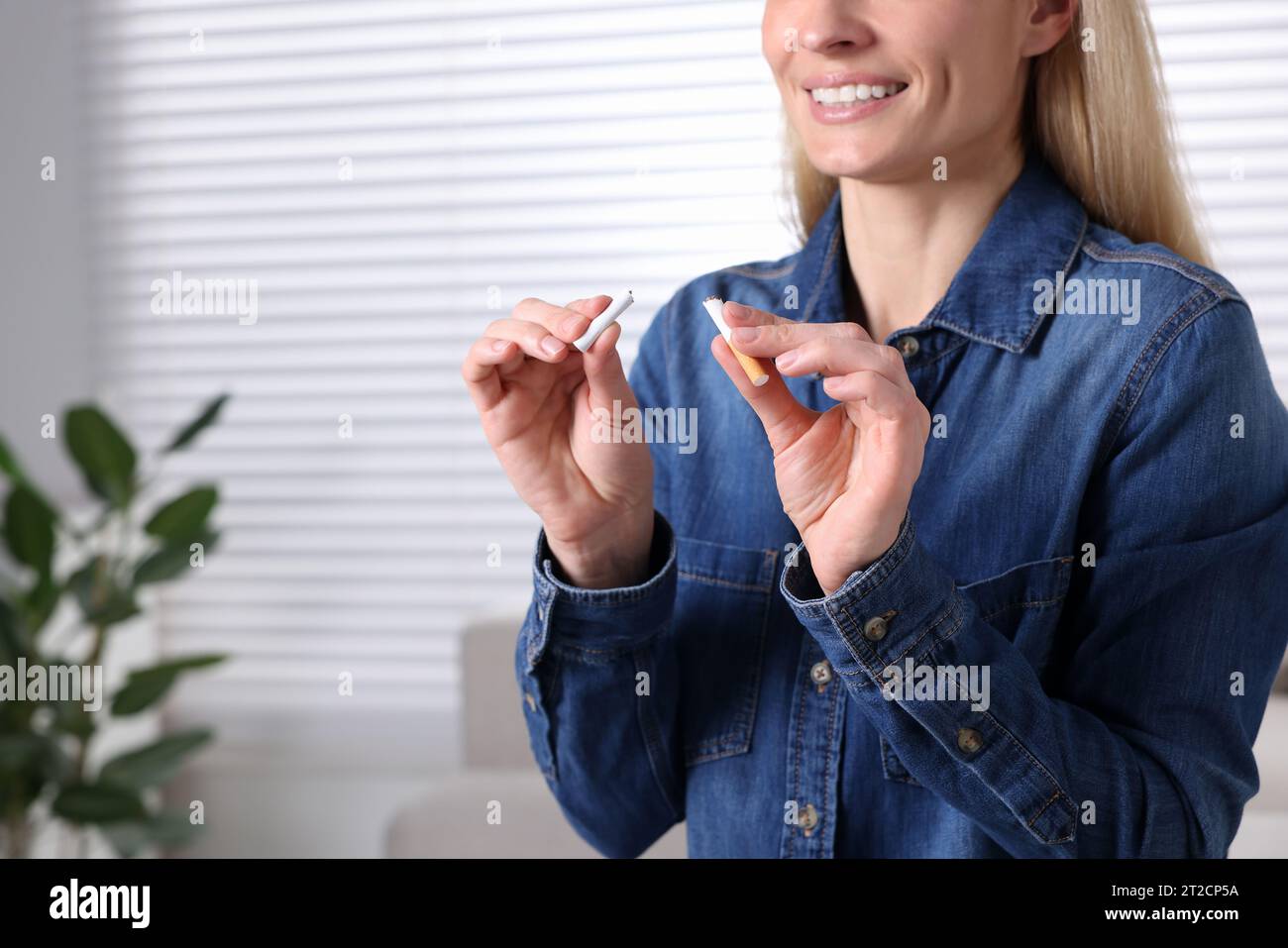 Quitting smoking concept. Woman with broken cigarette on blurred