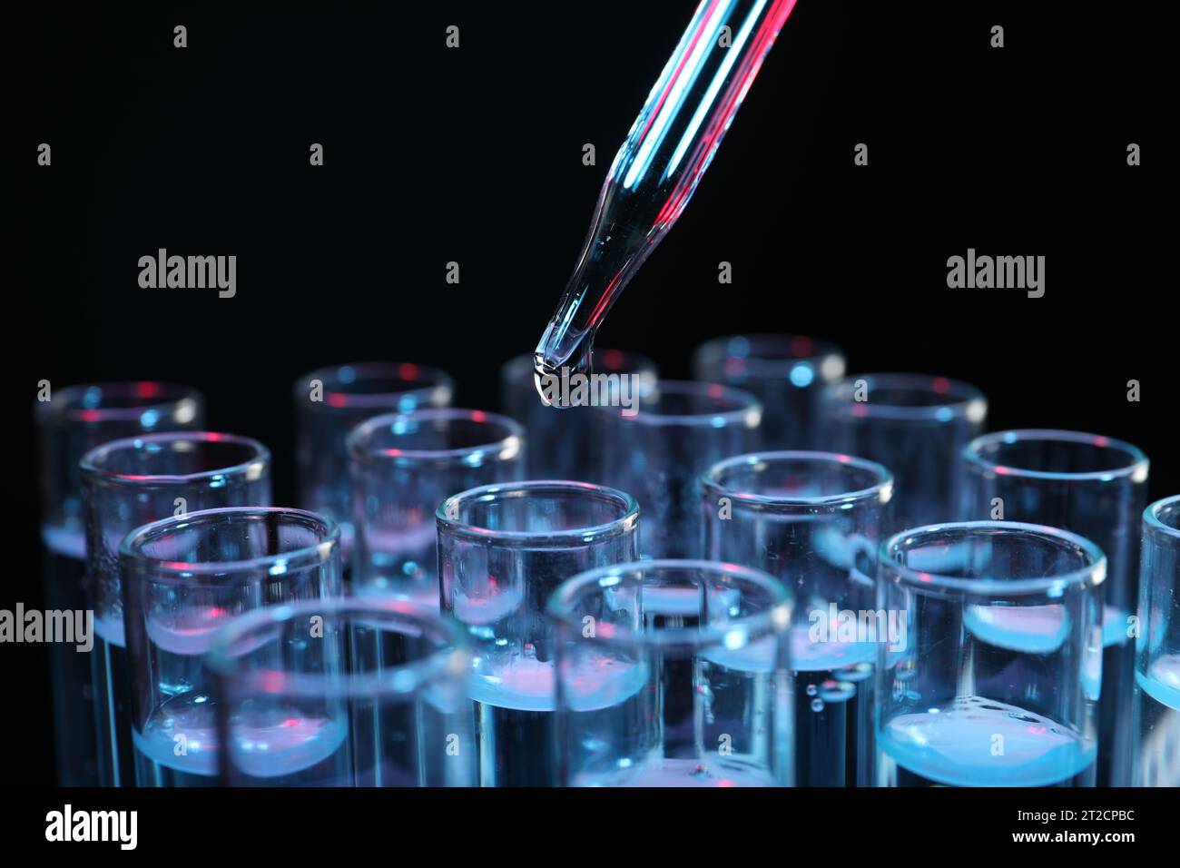 Dripping reagent into test tube on black background, closeup ...