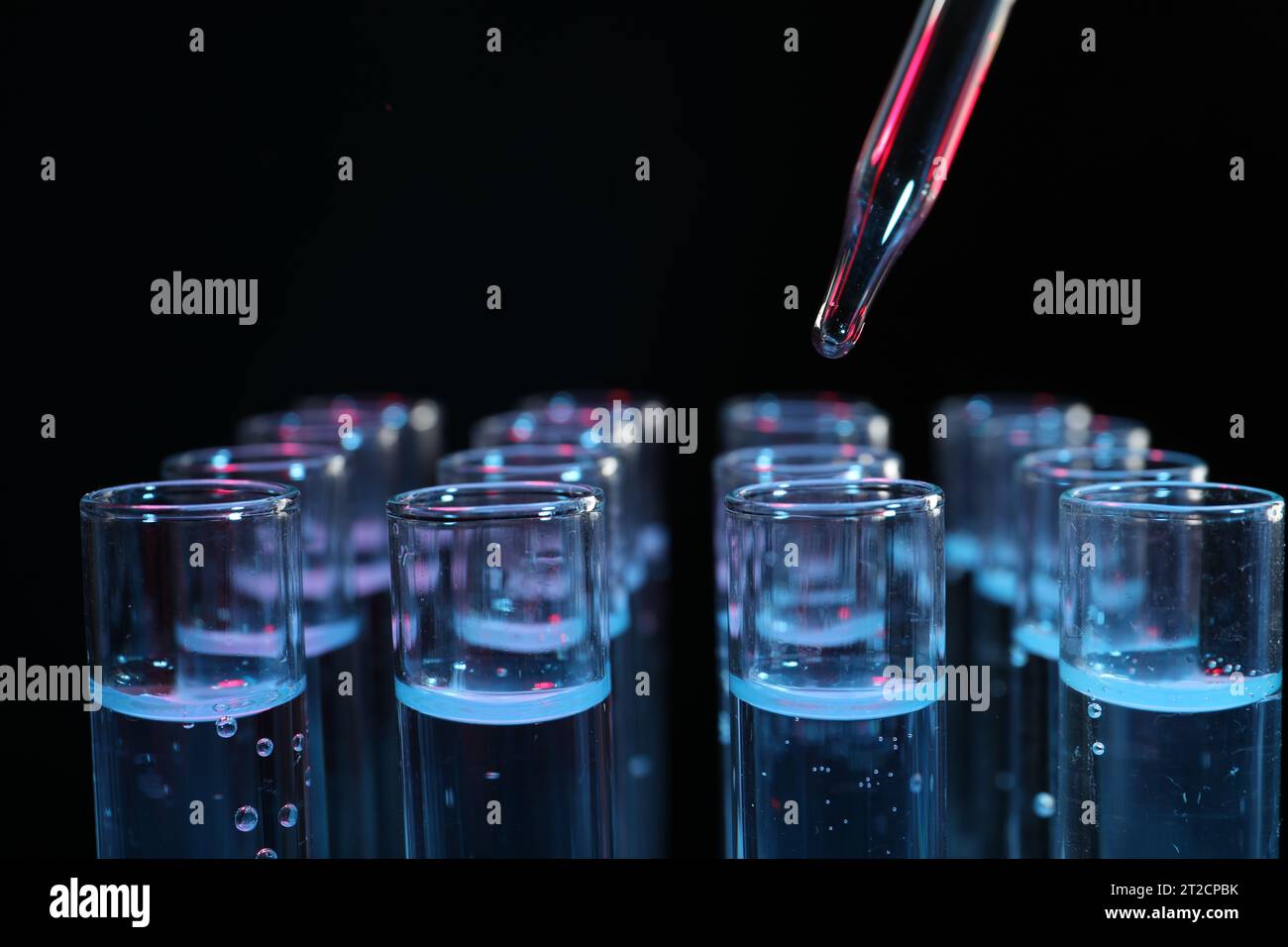 Dripping reagent into test tube on black background, closeup ...