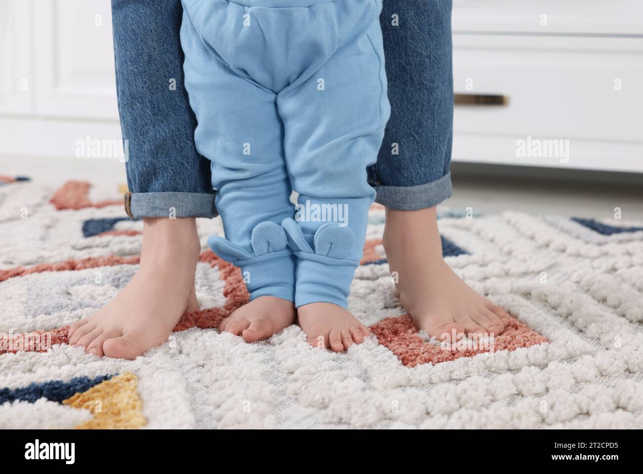 Walk On Rug Mother supporting her baby son while he learning to walk on carpet ...