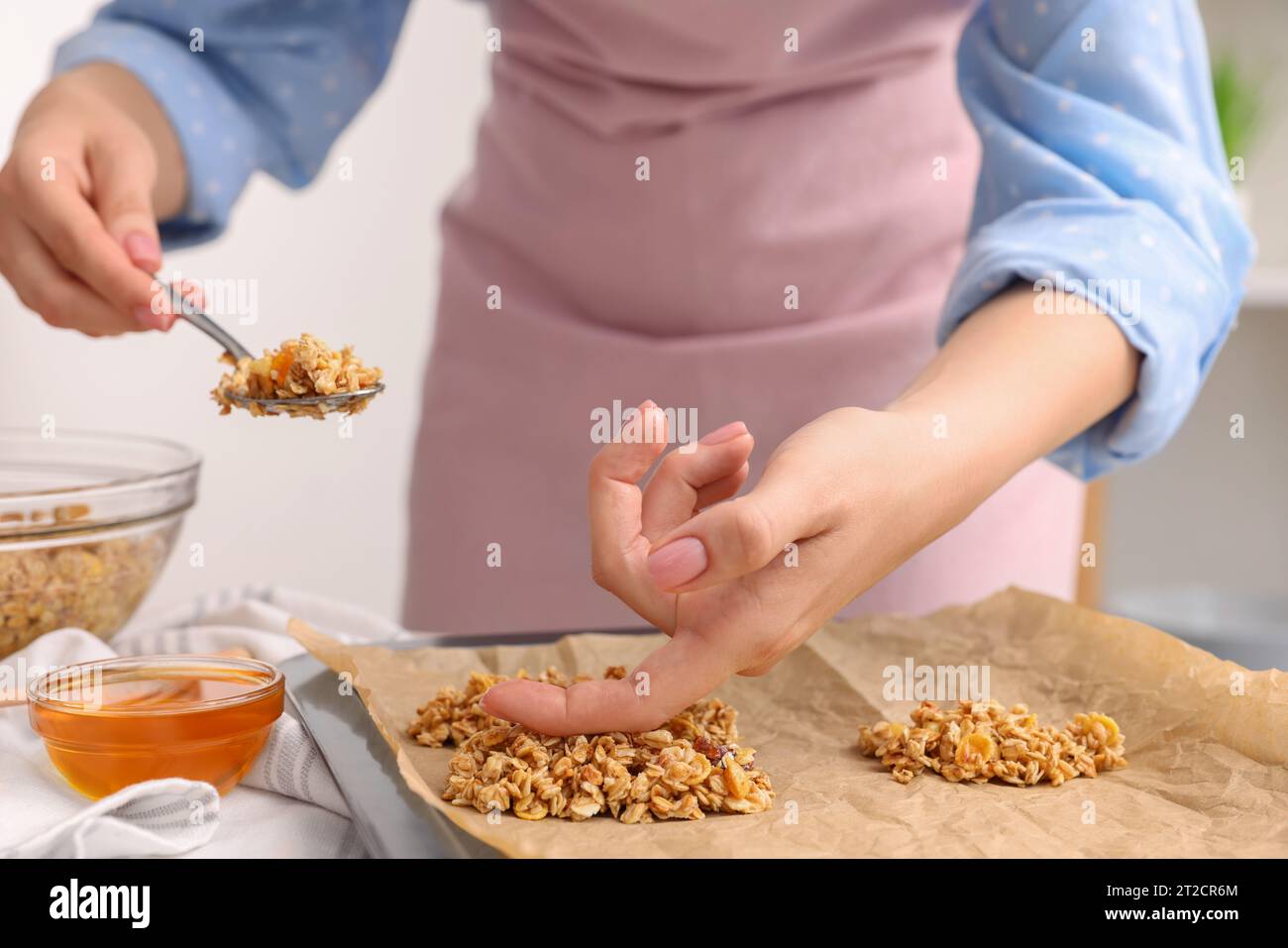Making granola bars. Woman putting mixture of oat flakes, dry fruits