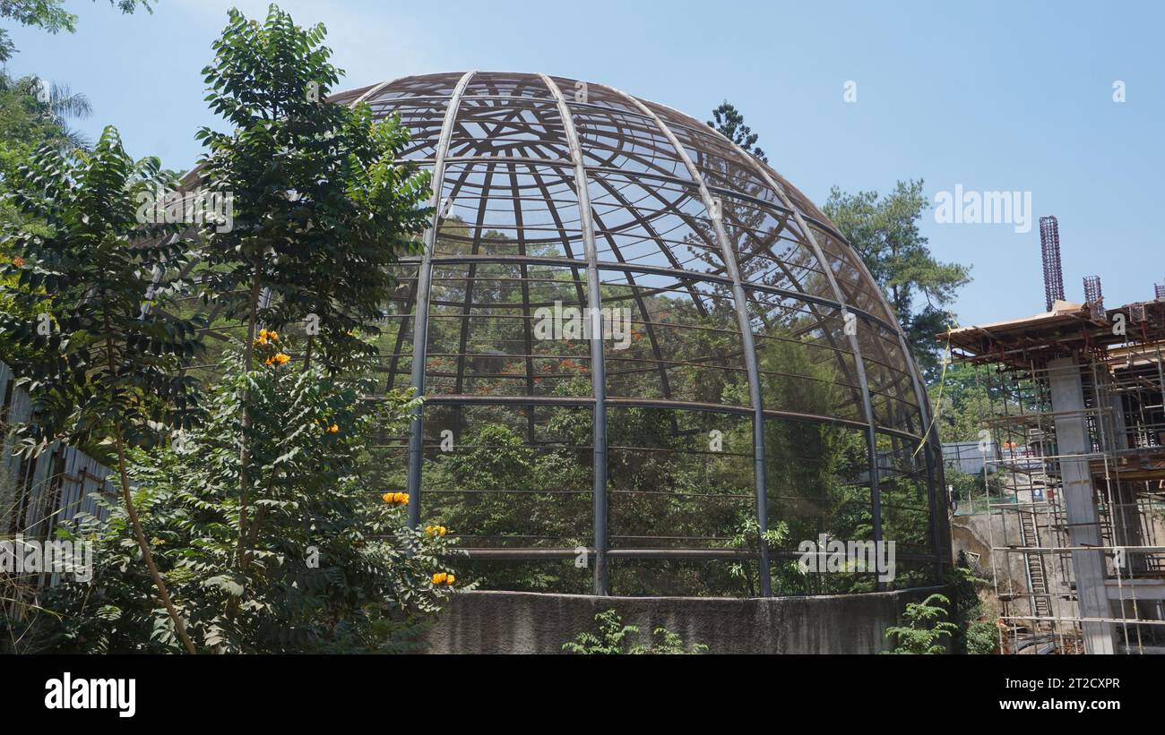 Large metal dome aviary for bird conservation next to a building construction site Stock Photo