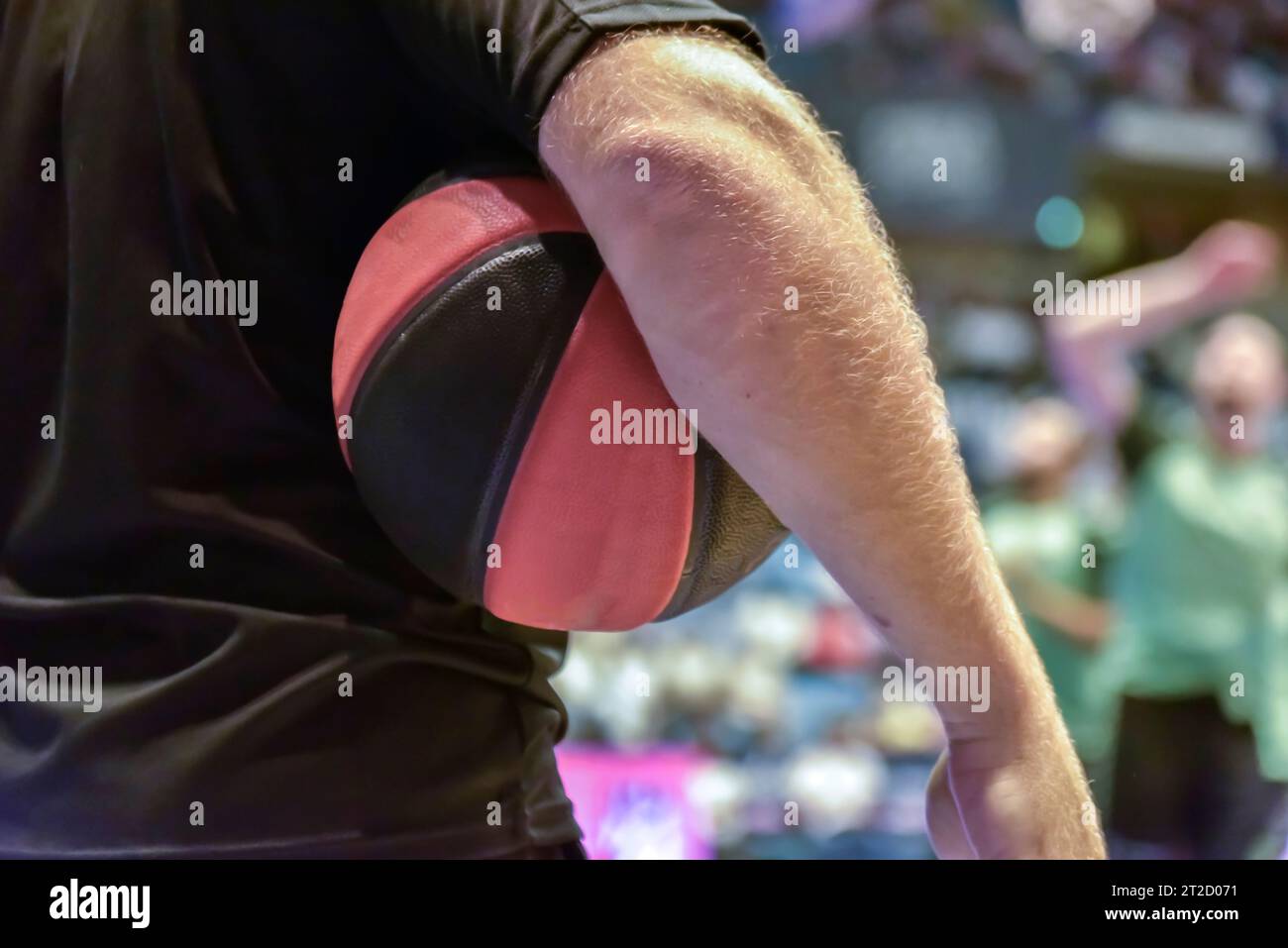 close-up of a basketball held by the referee against his body. Stock Photo