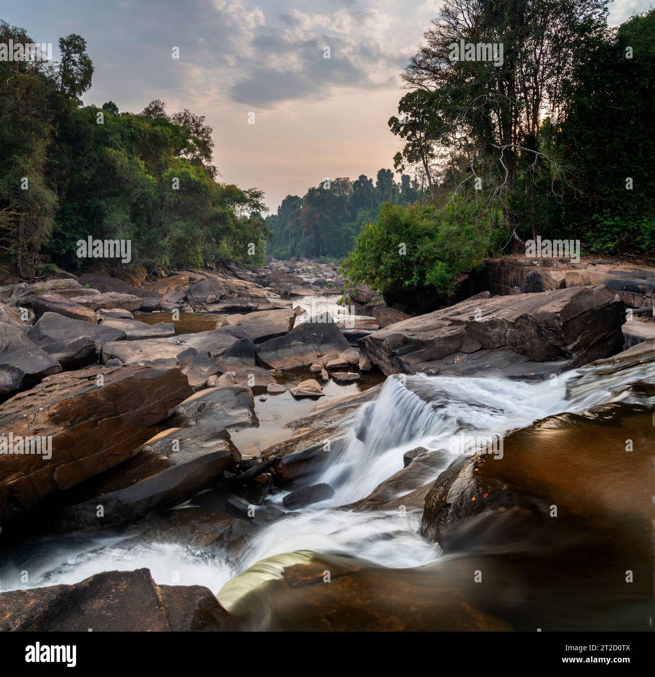 On the Pakse Loop route,long exposure water motion,over wonderful rock formations and large shining boulders,looking into the sunset along the Vang Ng Stock Photo