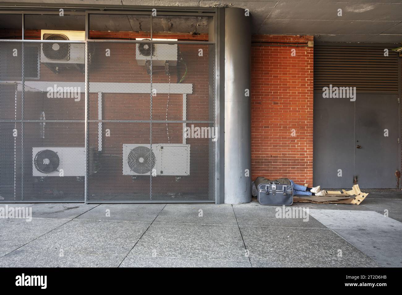 A homeless man taking a nap in a corner sheltered from prying eyes ...