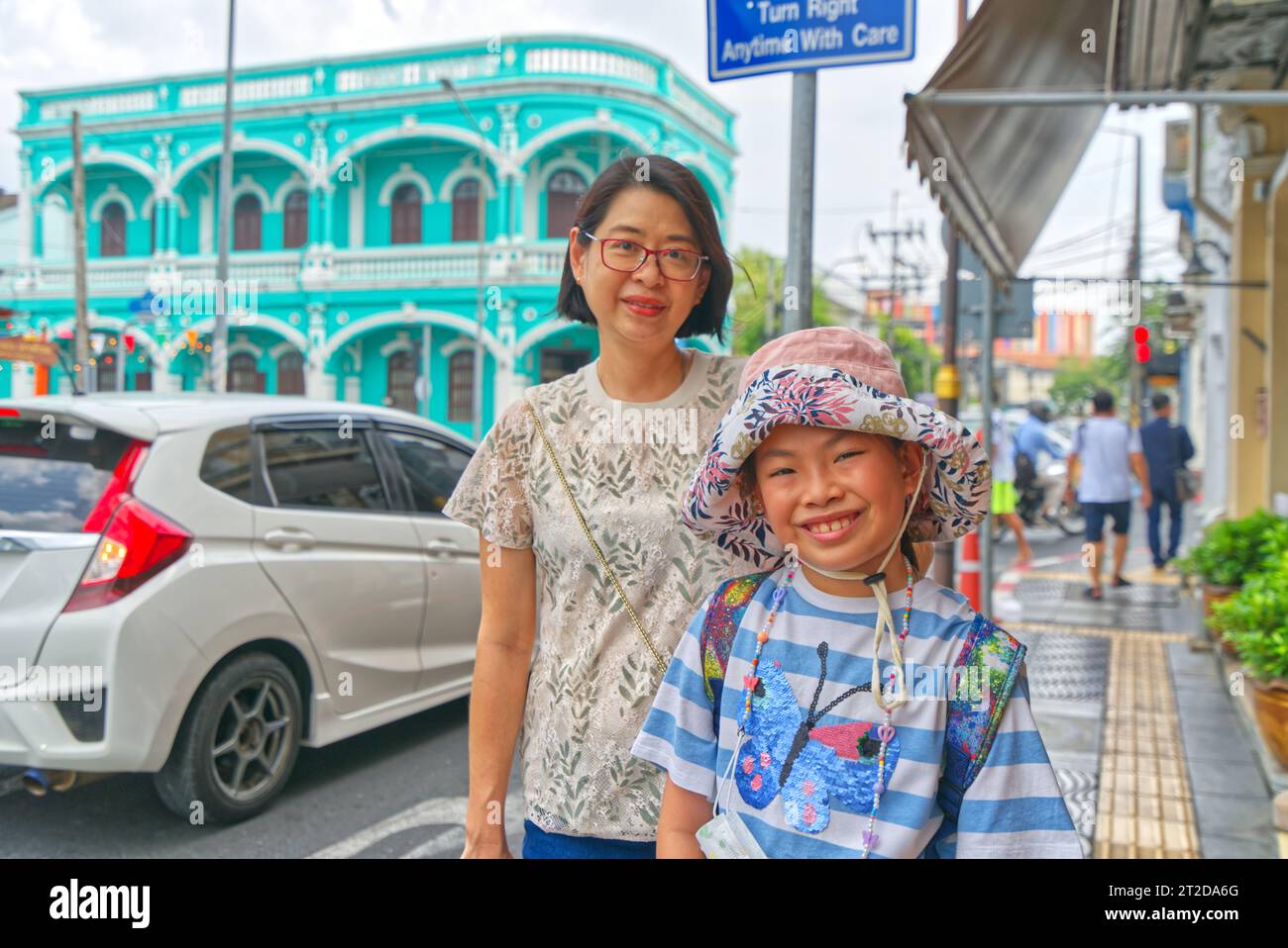 Portrait of Asian middle-aged mother and little daughter on the street of old town Phuket, landscape image. Stock Photo