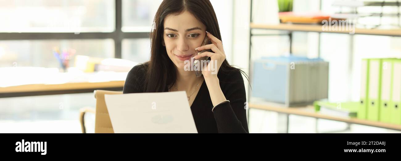 Secretary Reading Satisfied secretary listens to client on phone reading paper Stock ...