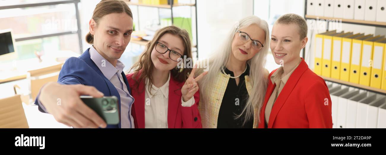 Man holds smartphone taking selfie with female colleagues Stock Photo
