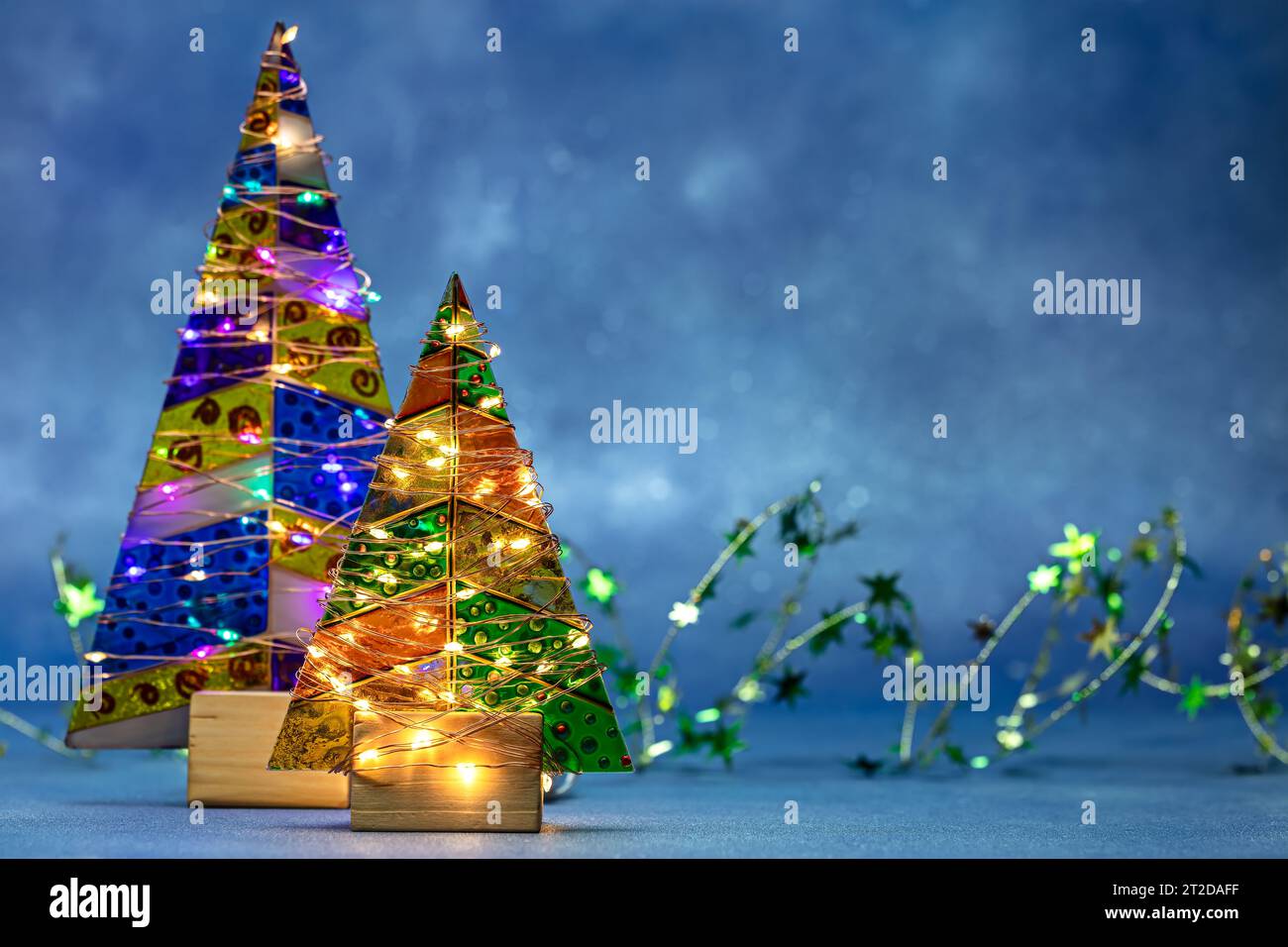 festive decorated christmas trees with glowing holiday garlands lights. Stock Photo