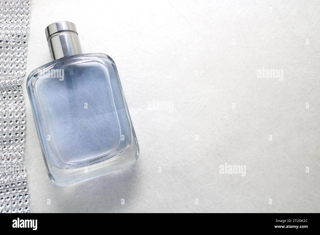 Blue beautiful glass transparent fashionable glamorous bottle of cologne, perfume and ribbon of sparkling rhinestones, diamonds and a place for a simp Stock Photo