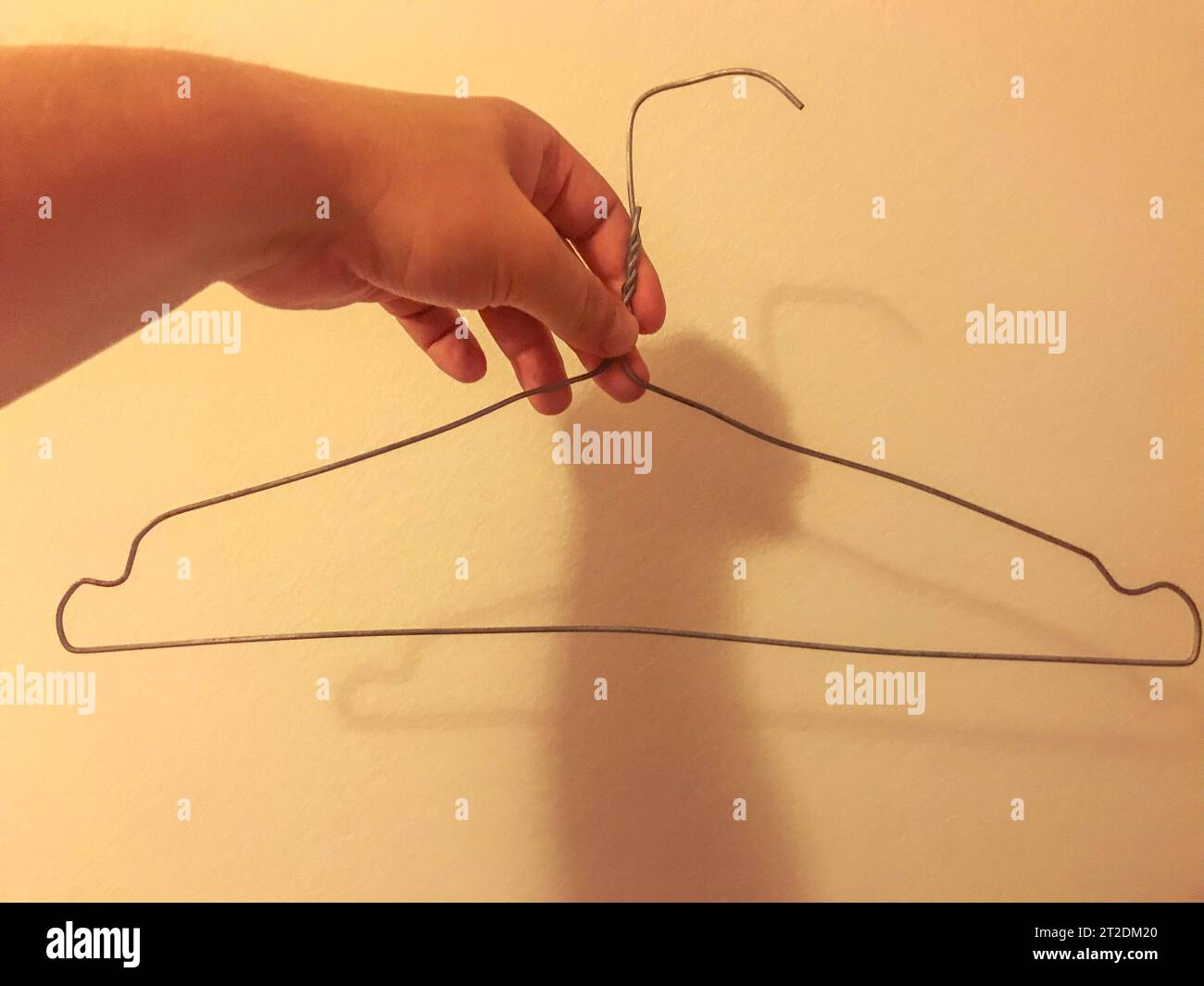 homemade wire hanger for clothes. clumsy, uneven hanger with your own hands. storing clothes in a poor man's wardrobe. Stock Photo