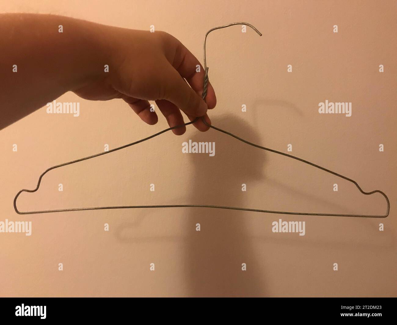 Homemade clothes hanger made of wire. Poor clothes rack in a cheap hotel room. Stock Photo