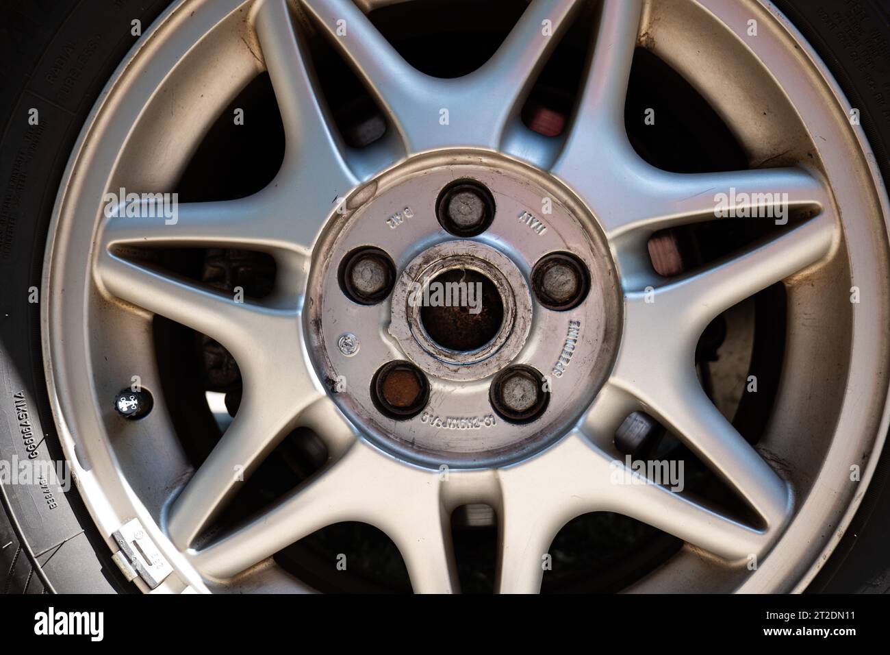 Used car alloy wheel with spokes and visible bolts. Close up shot, no
