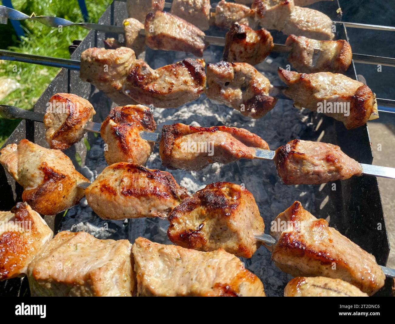 Cooking Grilled Meat. Servicemen prepare barbecue. A man in a military camouflage uniform fry the meat. Rest of the military at the festival. Army cui Stock Photo