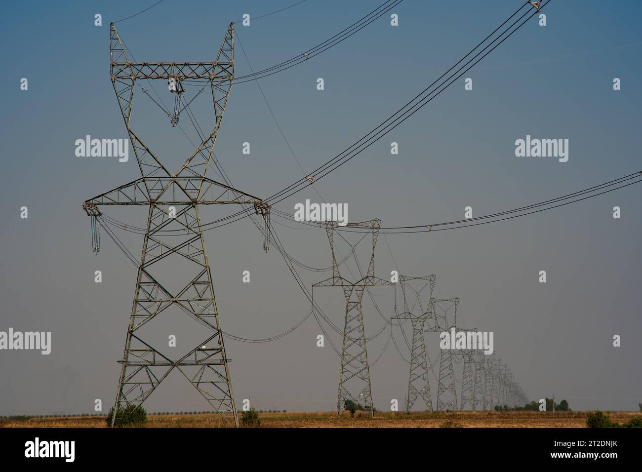 Highvoltage power line transmission towers or pylons in a field in Europe. No people Stock
