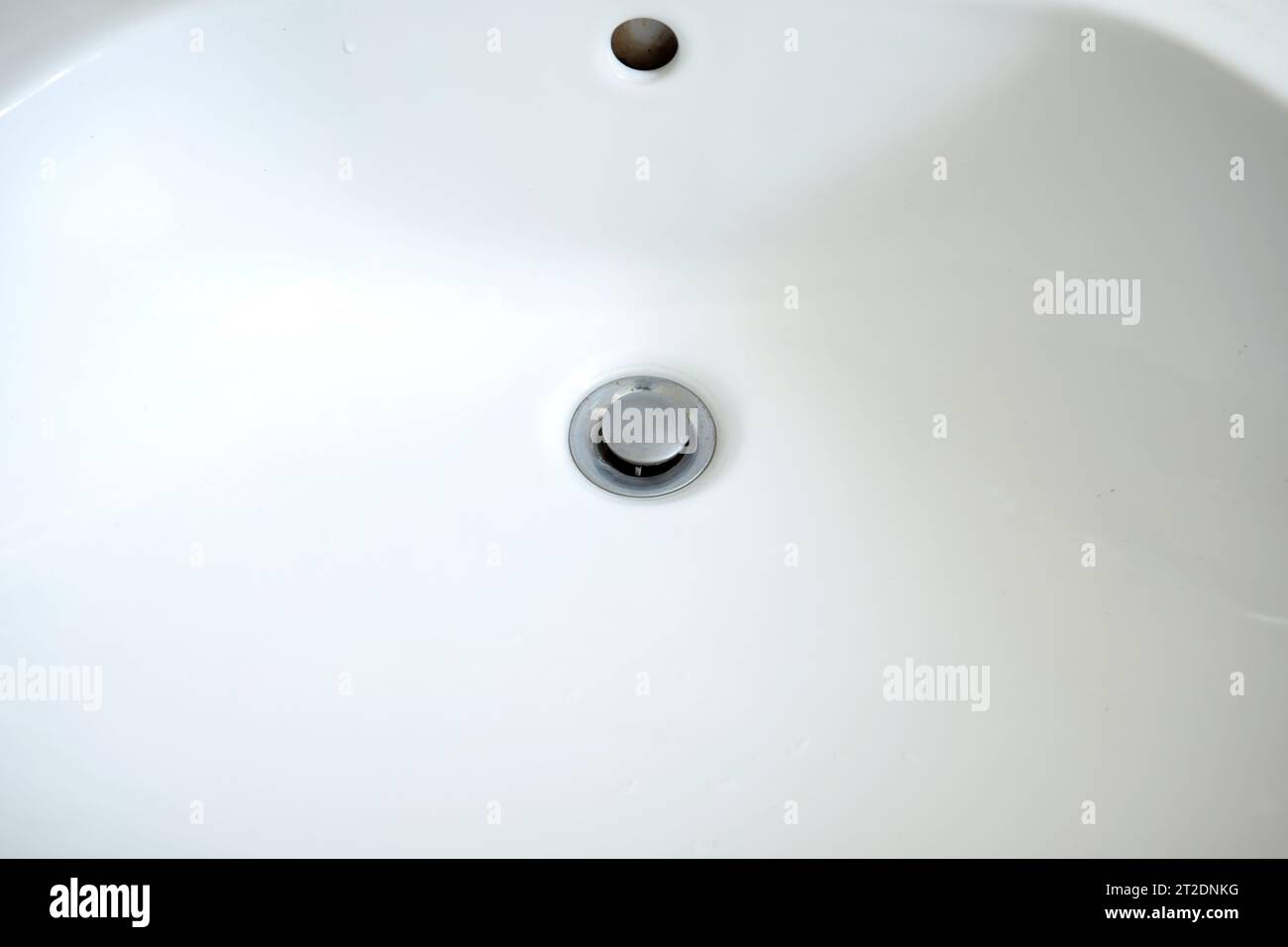 Bathroom sink draining hole with metal plug. Top view, close up, no