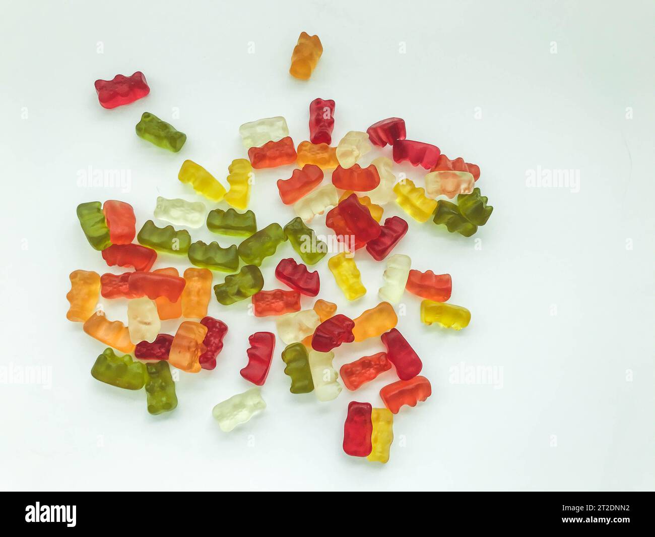 gummy bears of different colors lie on a matte white background. delicious variety of sweets. gelatinous gummies desired. delicious bears, edible swee Stock Photo