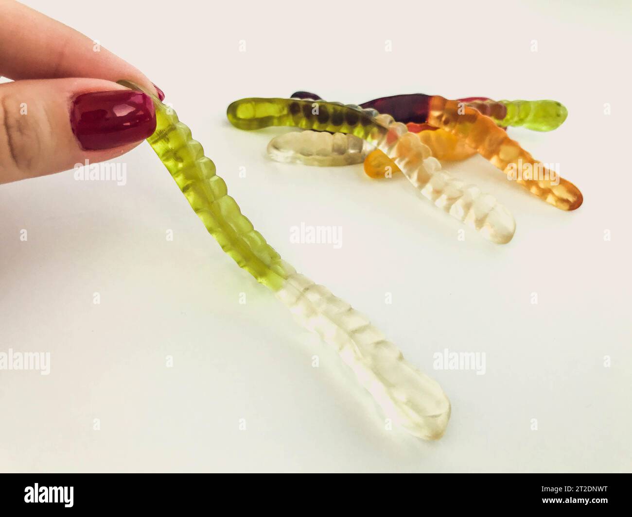gummy, gelatinous worms are held in her hand by a girl with a bright
