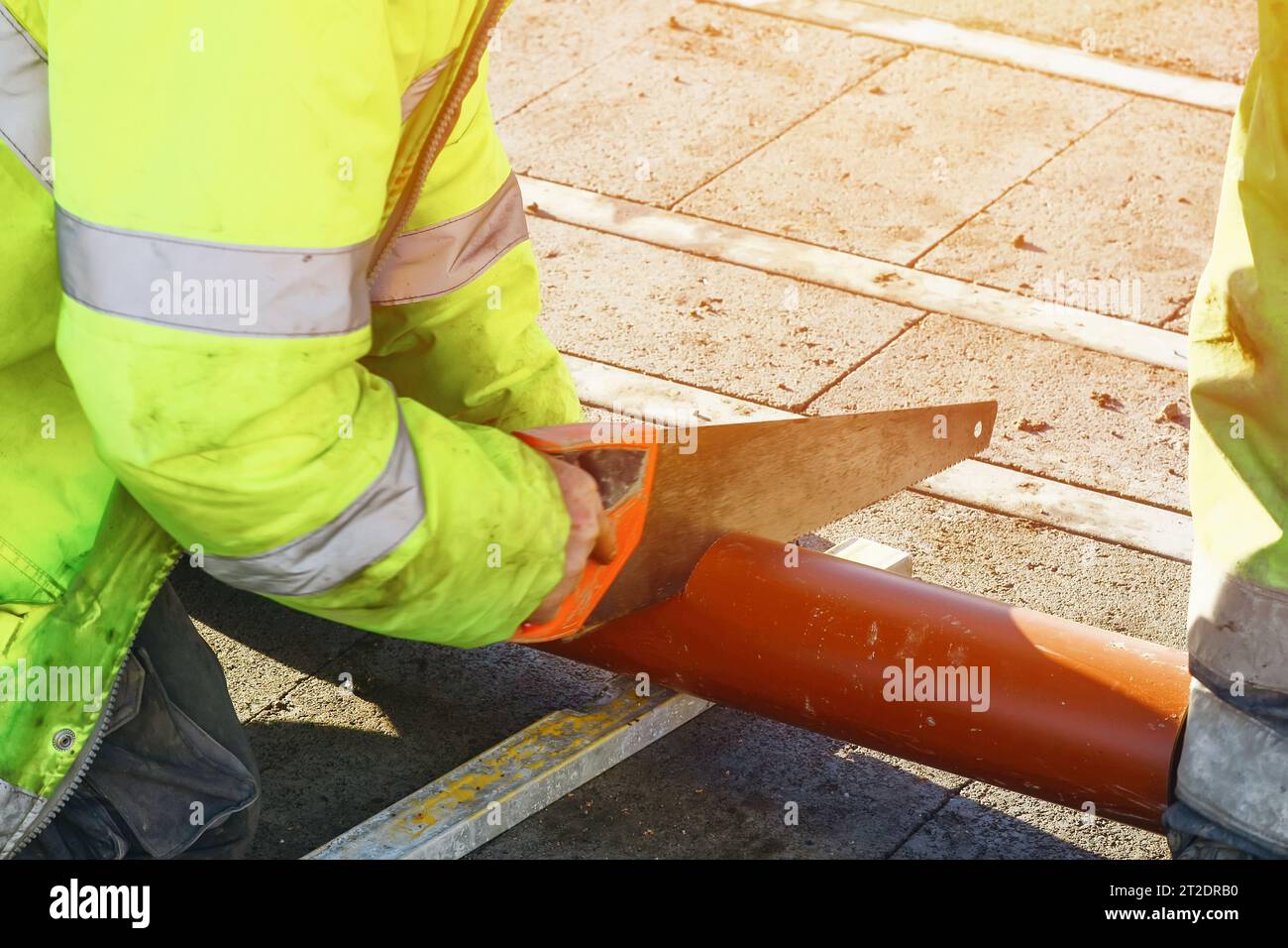 Builder cutting plastic pipe with hand saw during new house internal
