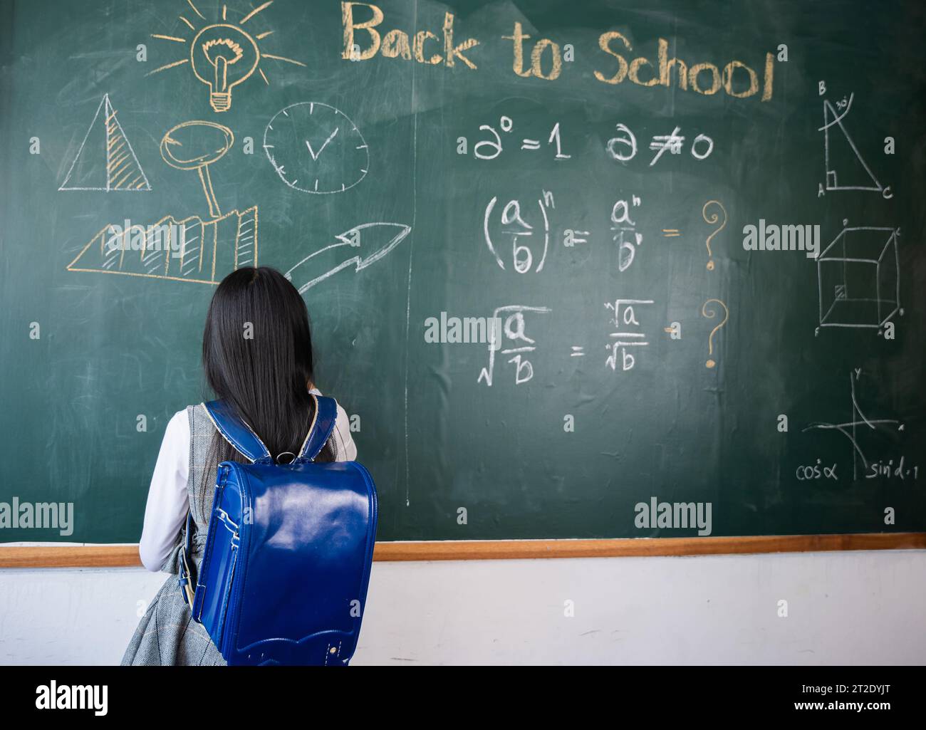Back view of school girl on science lesson in classroom write an answer ...
