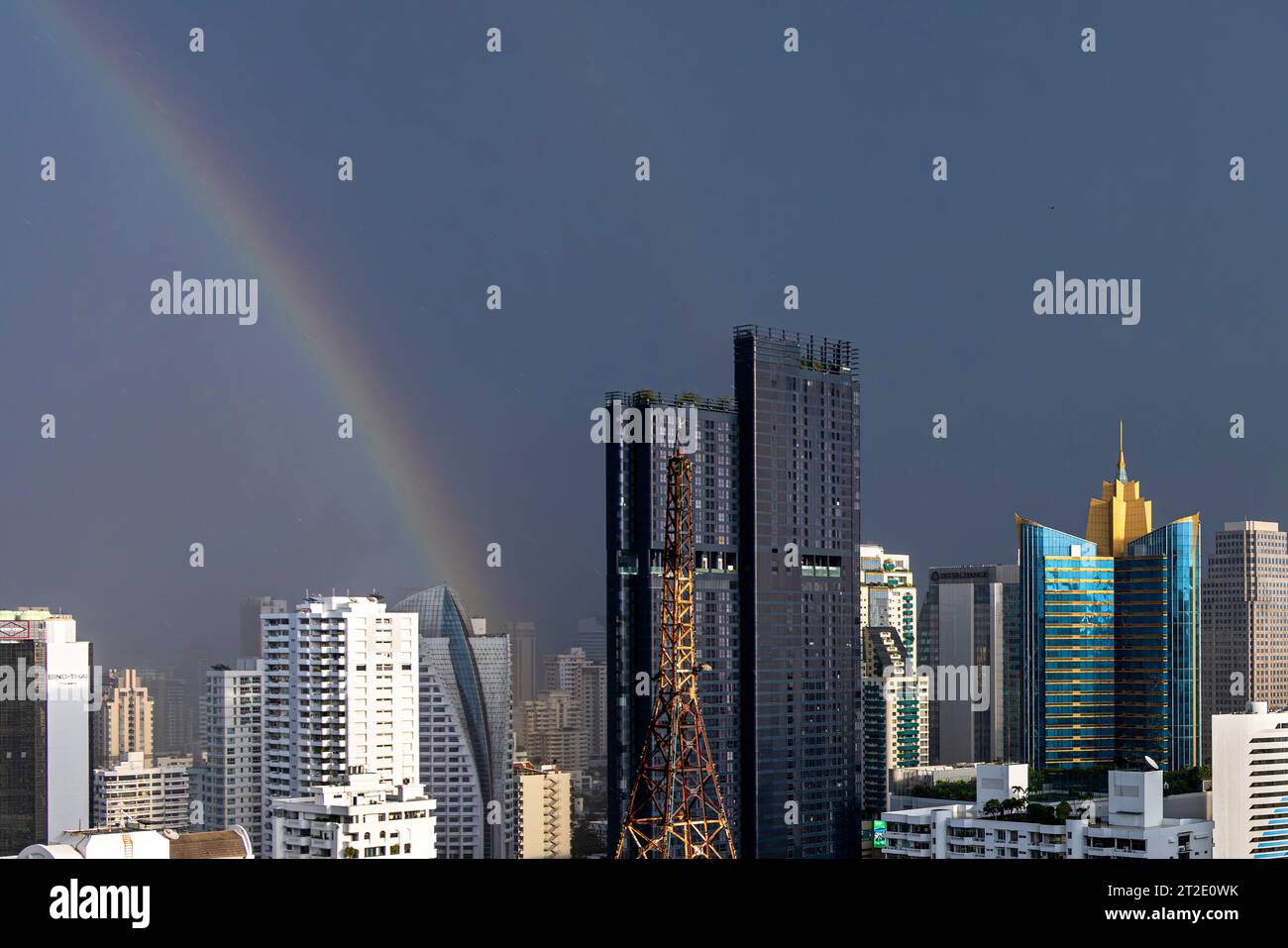 Rainbow, rain, sun and storm clouds over Bangkok high rise skyline, Sukhumvit area, Thailand Stock Photo