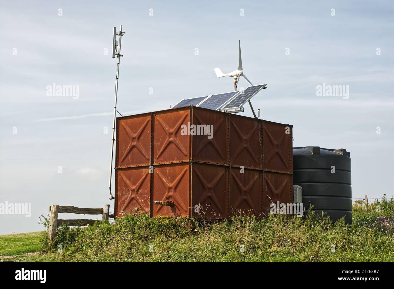Photovoltaic solar panels and wind powered generator on water tanks in rural location. England. Stock Photo