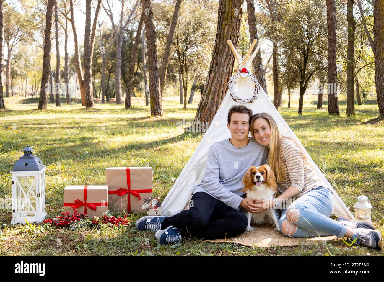 Smiling family of a young couple and a dog posing with Christmas decoration winter in the forest Stock Photo