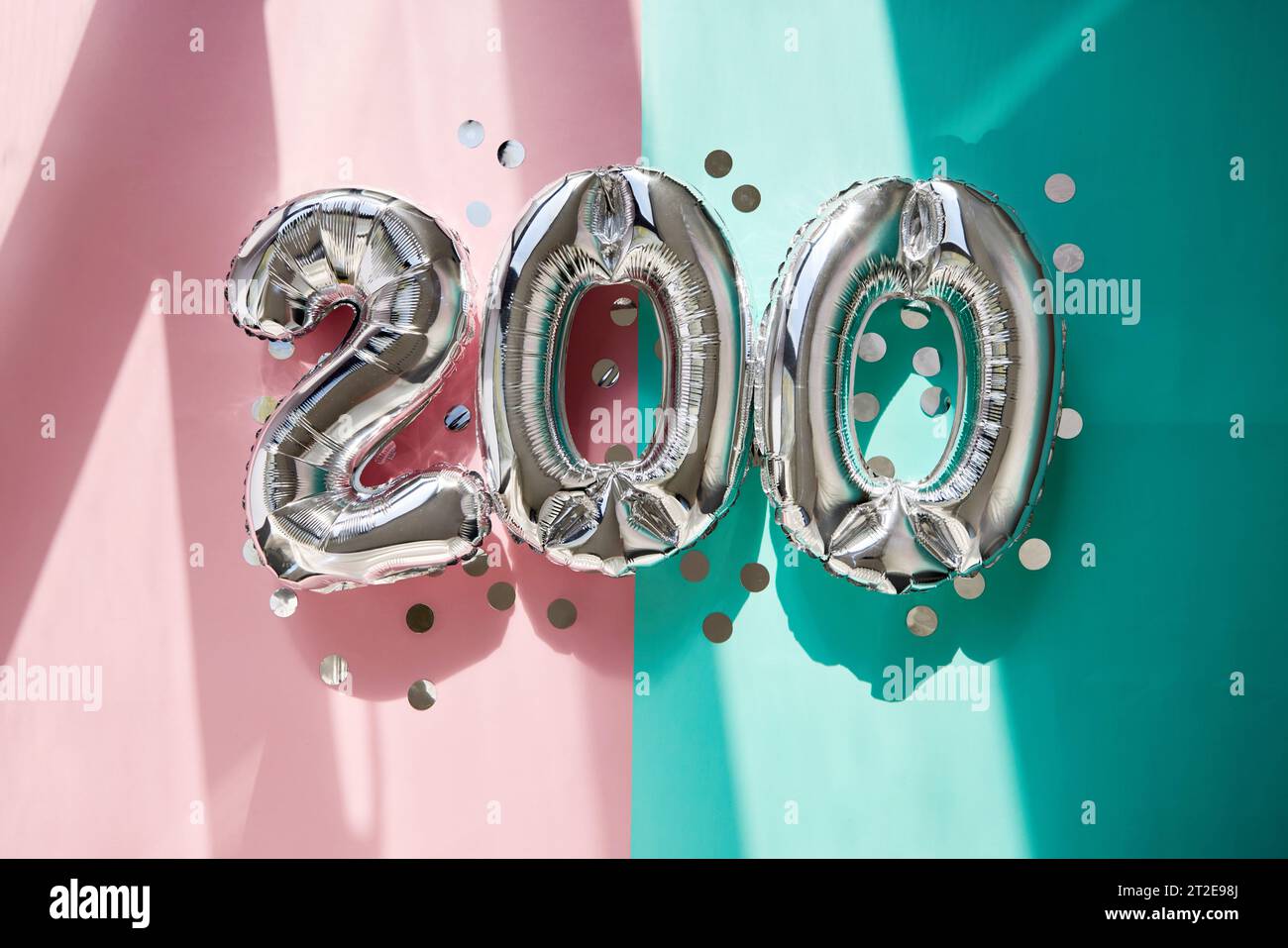 Silver numbers 200 two hundred balloons among confetti in sunlight on pink turquoise background celebration party. Greetings and congratulation Stock Photo