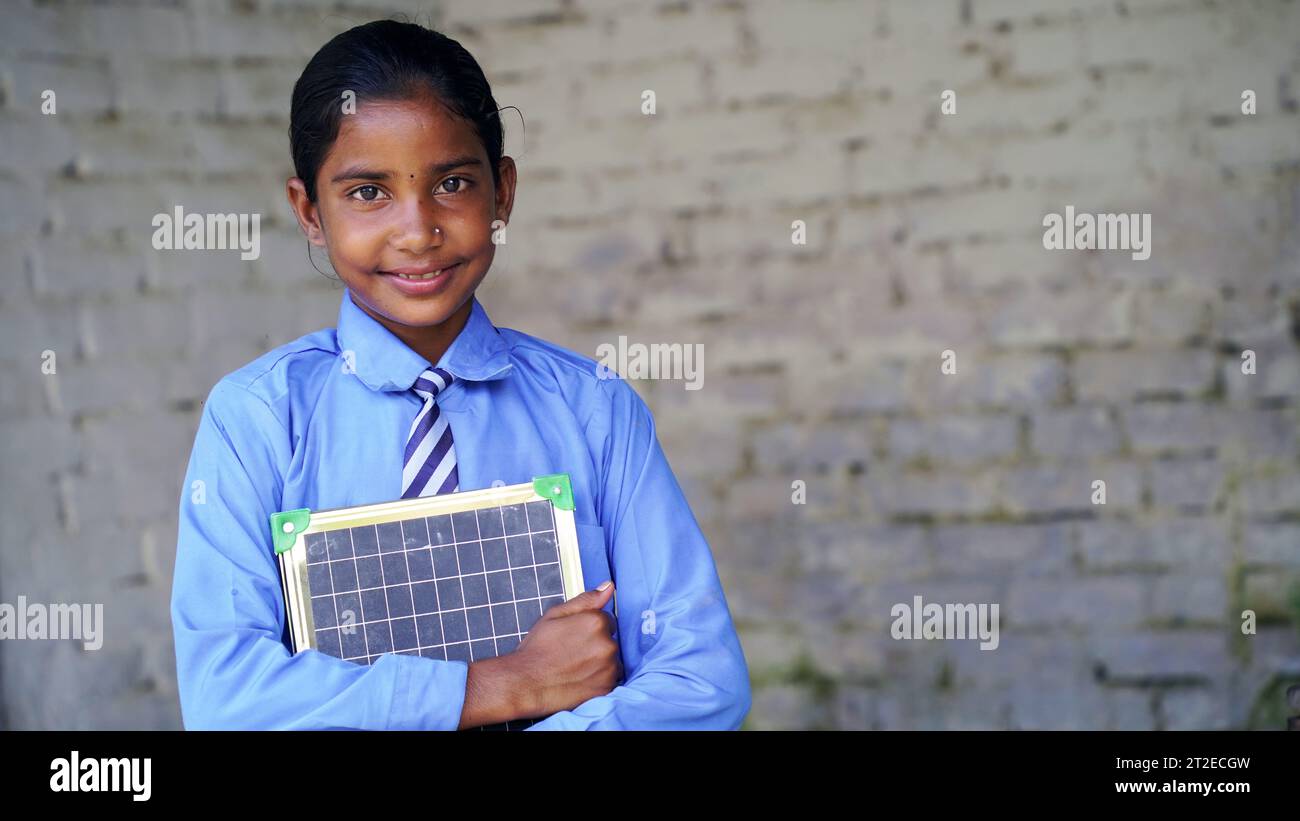 Portrait of happy cute little indian girl in school uniform holding ...