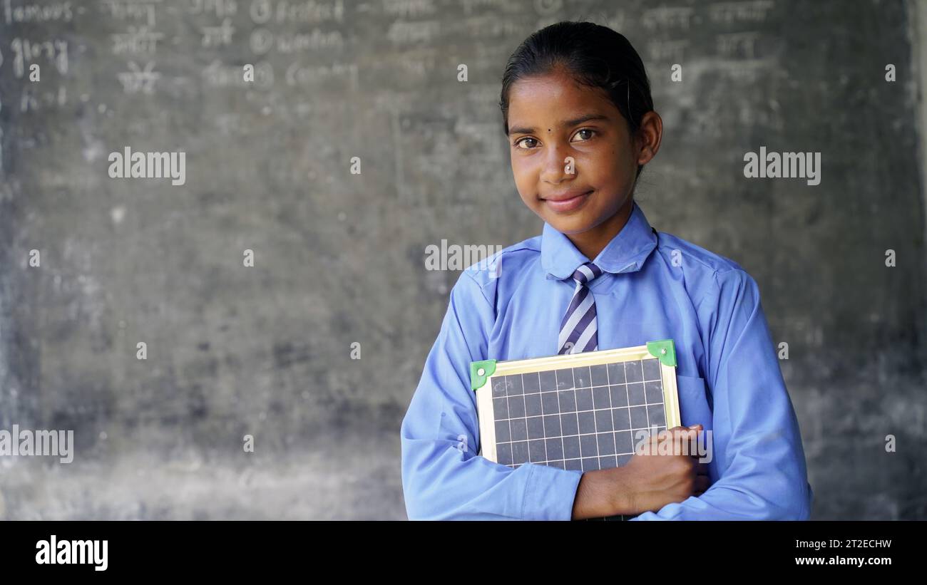 Portrait of happy cute little indian girl in school uniform holding ...