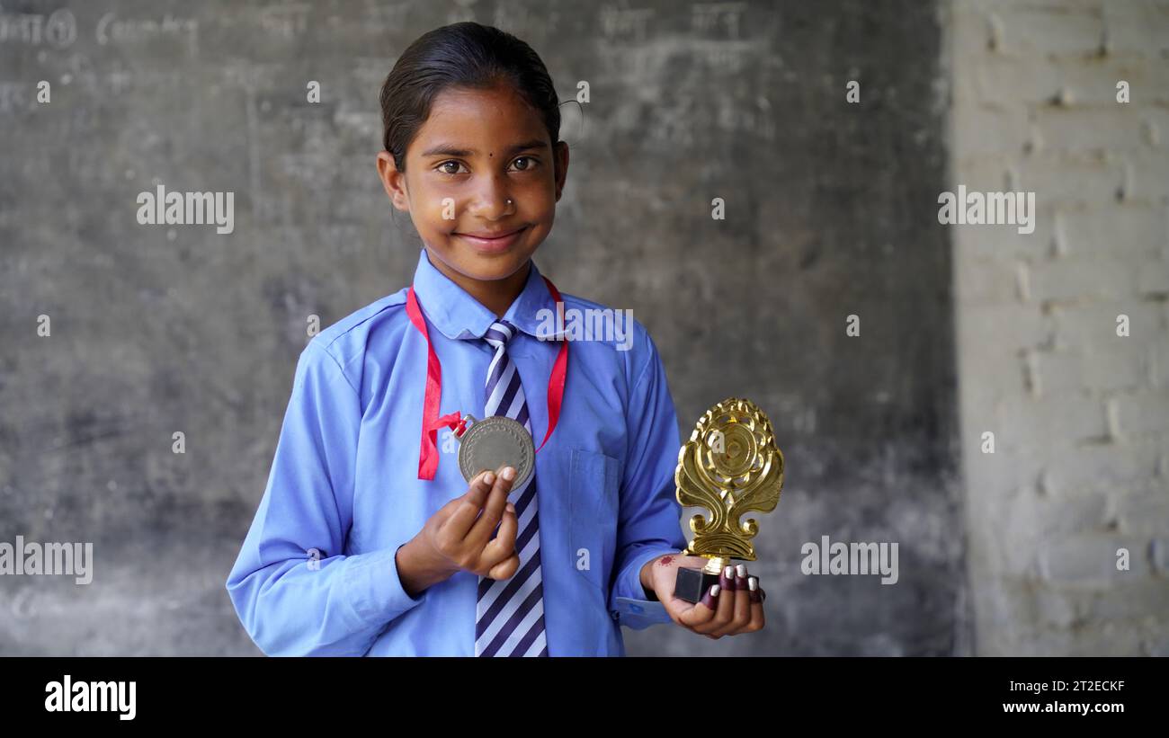 Portrait of a Happy School girl wearing school uniform celebrating victory trophy in hand. Education concept. skill india. child dreams Stock Photo