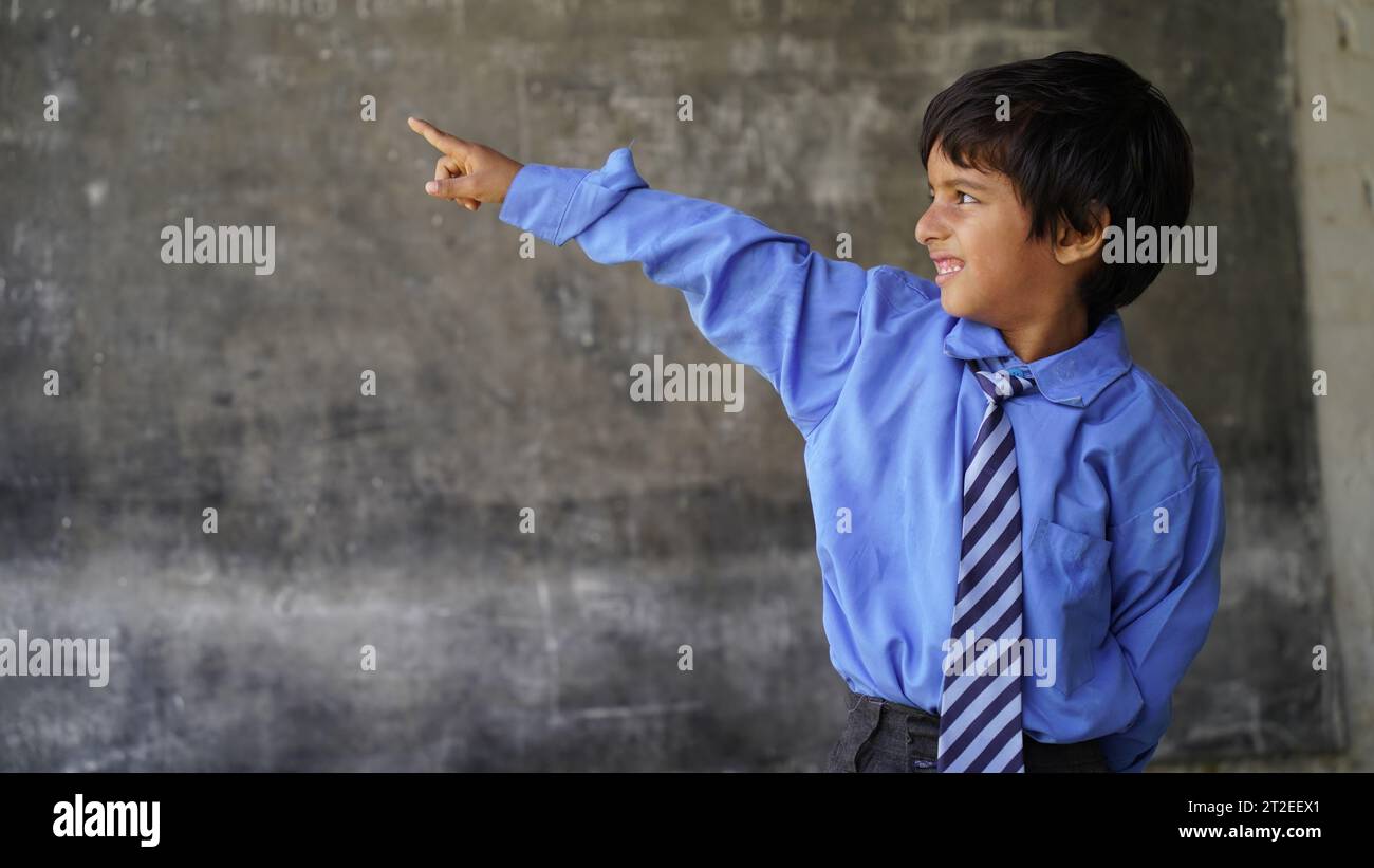 Indian school boy standing against blank chalkboard, intelligent and smart student, Education concept or Back to School Stock Photo