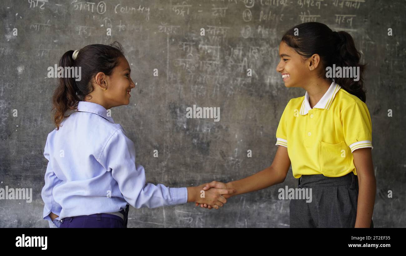 Happy Indian school girl child standing in front of black chalkboard