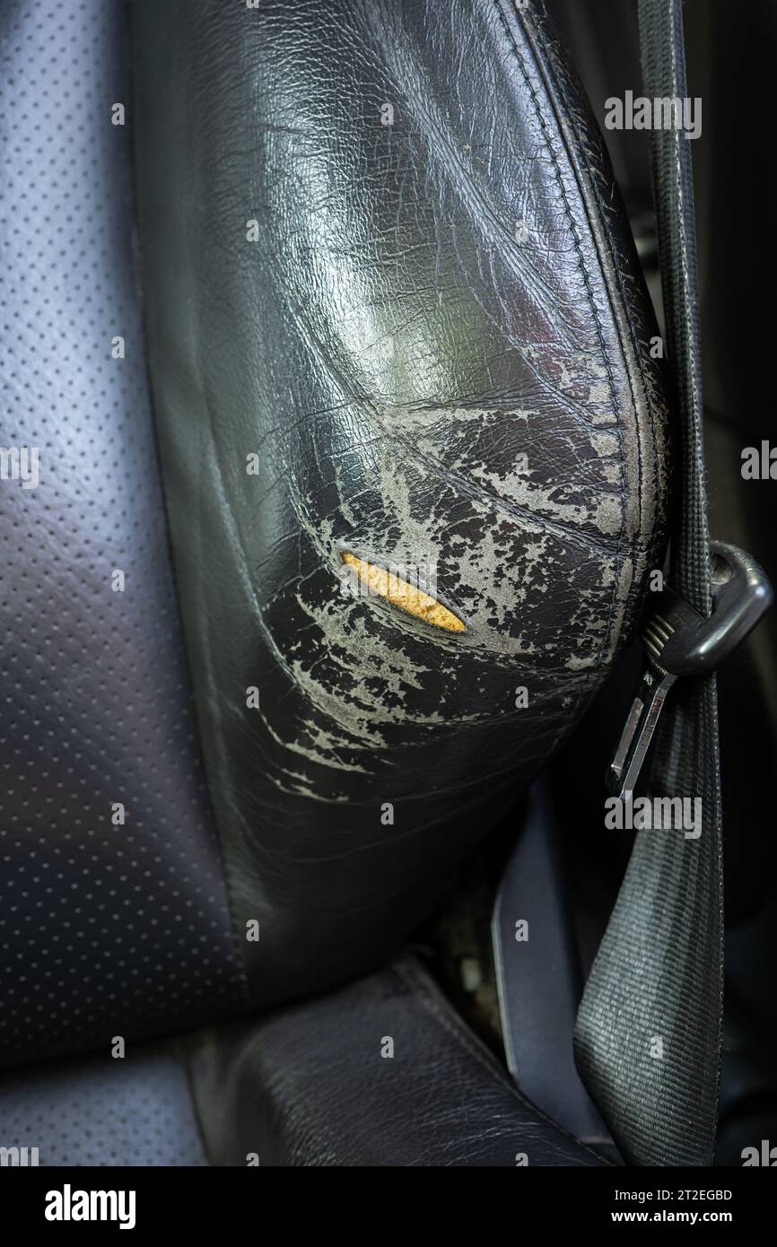 Ripped and torn natural leather car seat. Damaged leather, exposed foam
