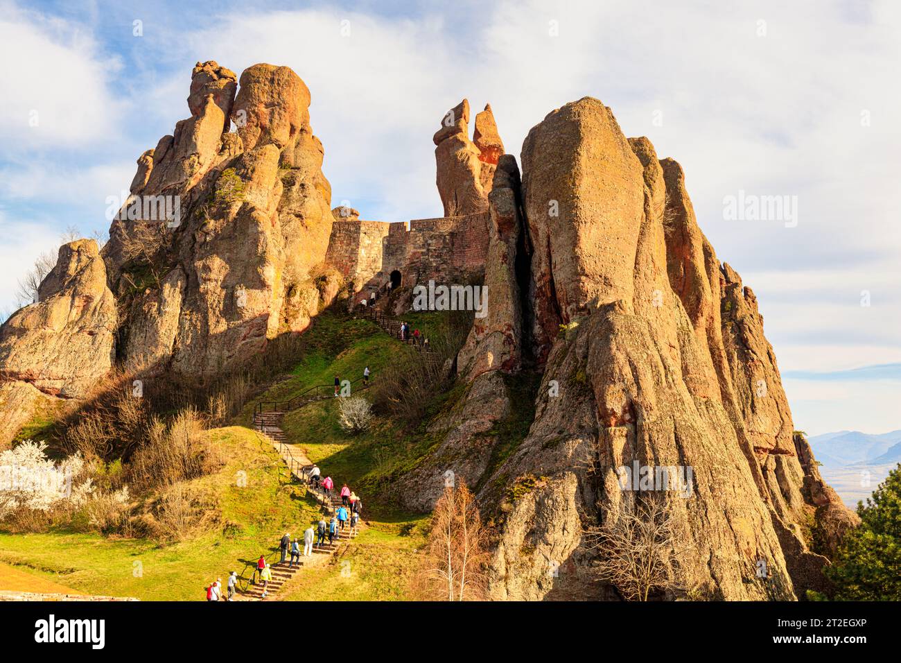 Group of active seniors hiking and climbing the steps leading to impressive rock formations  Belogradchik Fortress, Kaleto, Bulgaria Stock Photo