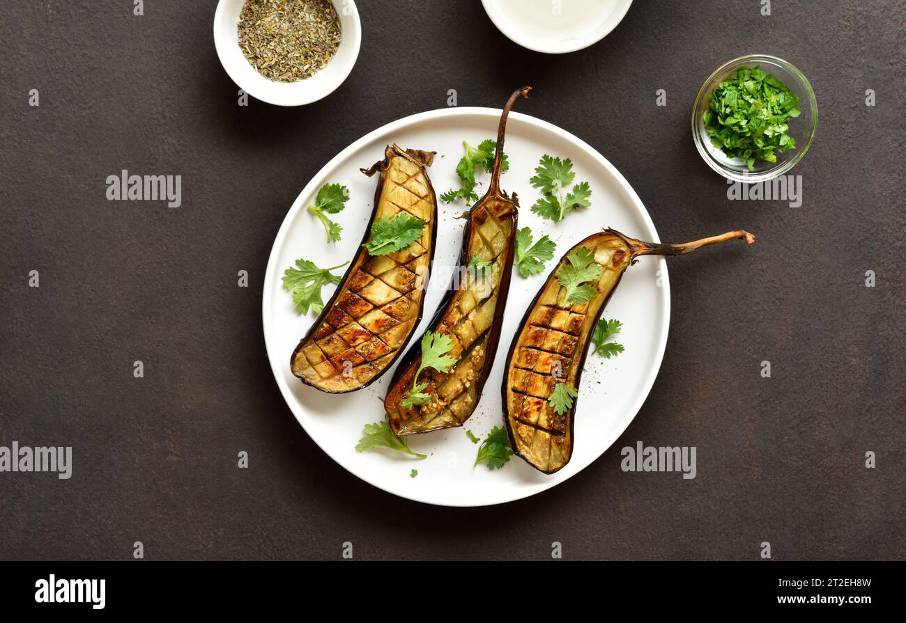 Grilled eggplant (aubergine) on plate over dark stone background. Top view, flat lay Stock Photo