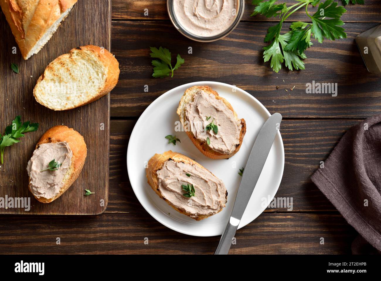 Toasted bread with chicken liver pate on cutting board over wooden background. Top view, flat lay Stock Photo