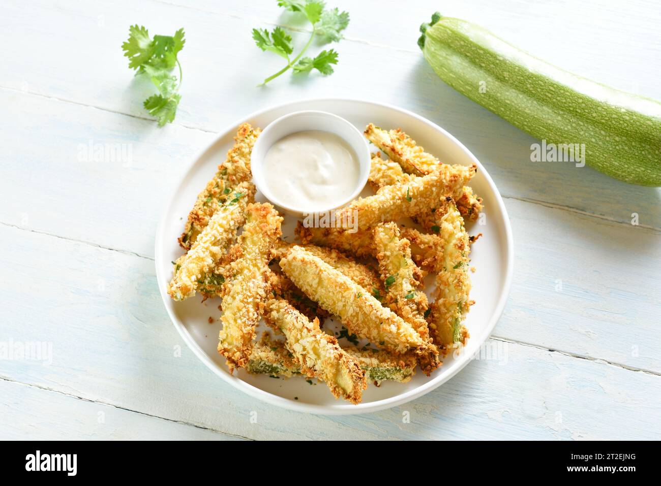 Homemade zucchini fries with dipping sauce on plate over light wooden background. Close up view Stock Photo