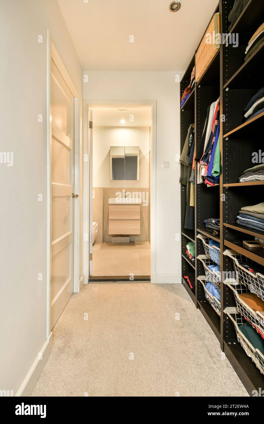 https://c8.alamy.com/comp/2T2EW4A/a-walk-in-closet-with-lots-of-clothes-on-the-shelfs-and-shelves-next-to-the-door-is-open-2T2EW4A.jpg