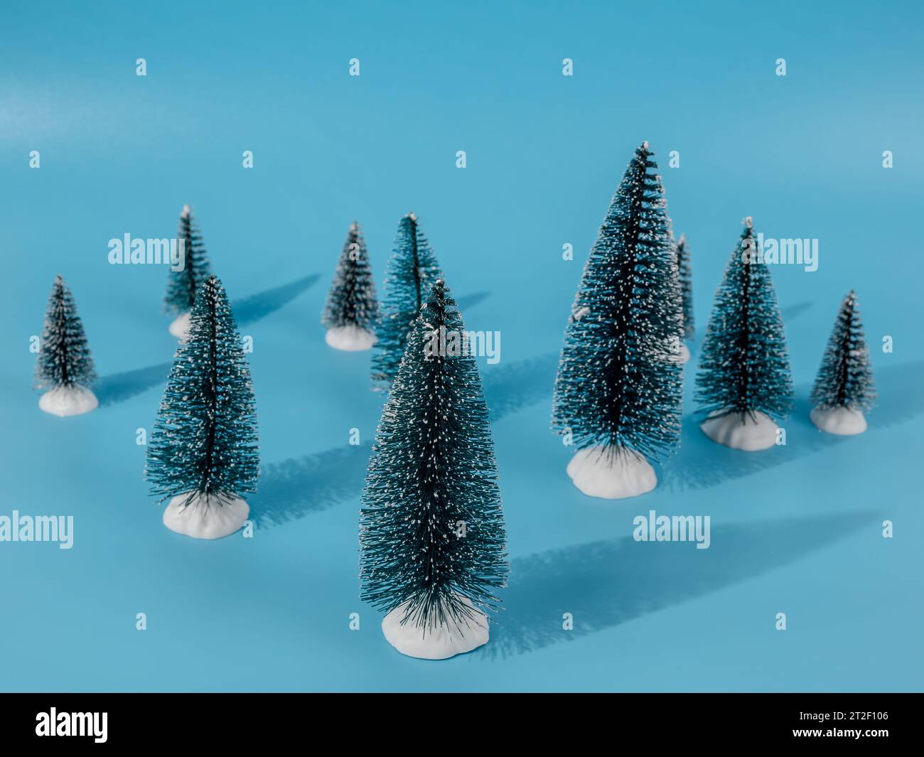 The photo shows several decorative artificial Christmas trees located on a bright blue background. The blue background creates a beautiful contrast an Stock Photo