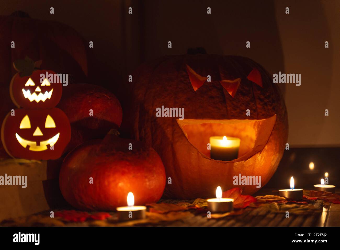 Augsburg, Bavaria, Germany - 18 October 2023: Halloween decoration in front of an apartment door in the dark. Burning candles glow around spooky decorated Halloween pumpkins in front of a door *** Halloween Dekoration vor einer Wohnungstüre bei Dunkelheit. Brennende Kerzen leuchten um gruselige verzierte Halloween Kürbisse vor einer Türe Stock Photo