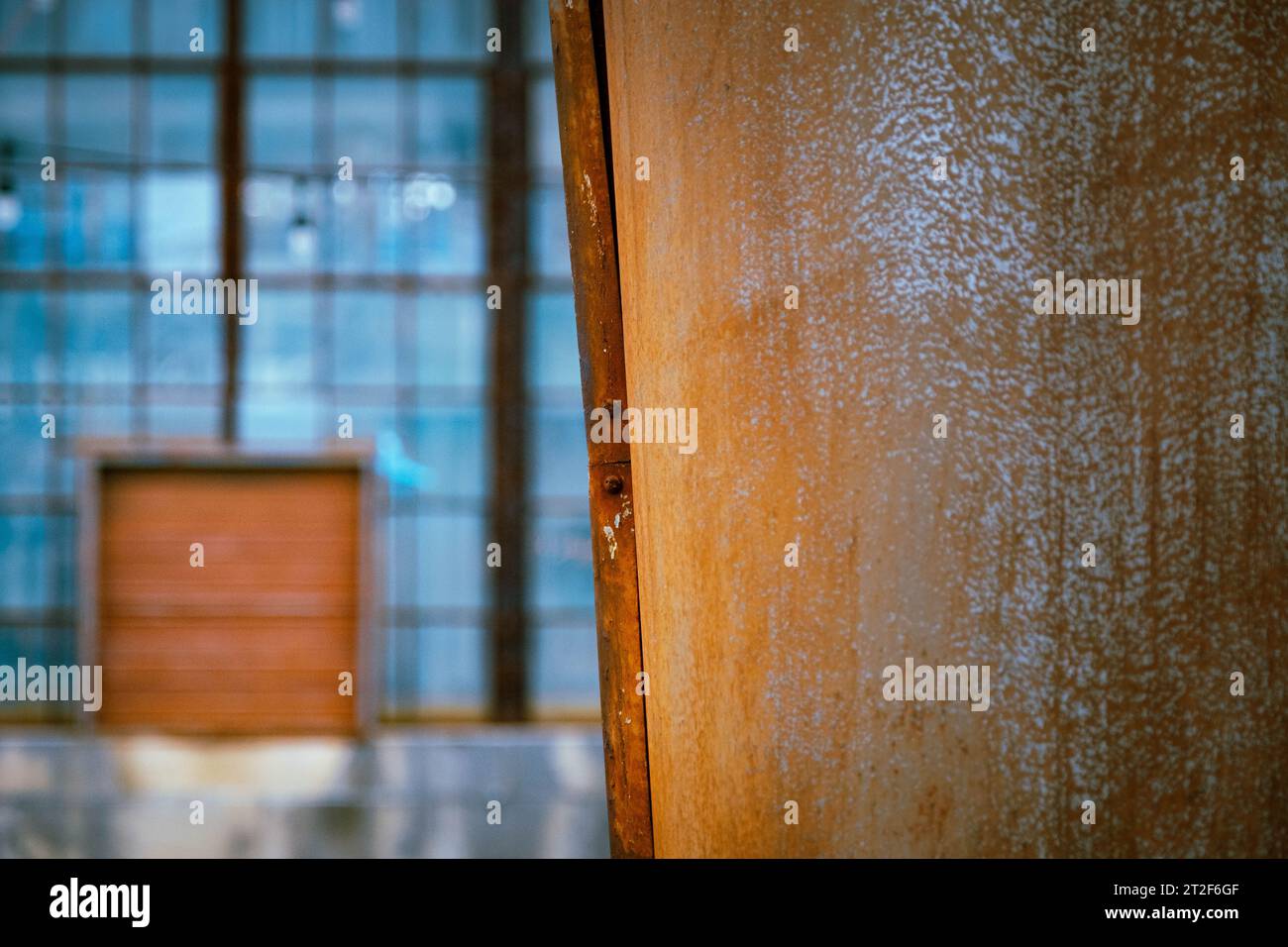 Rusted metal close up with old factory windows and door in background Stock Photo