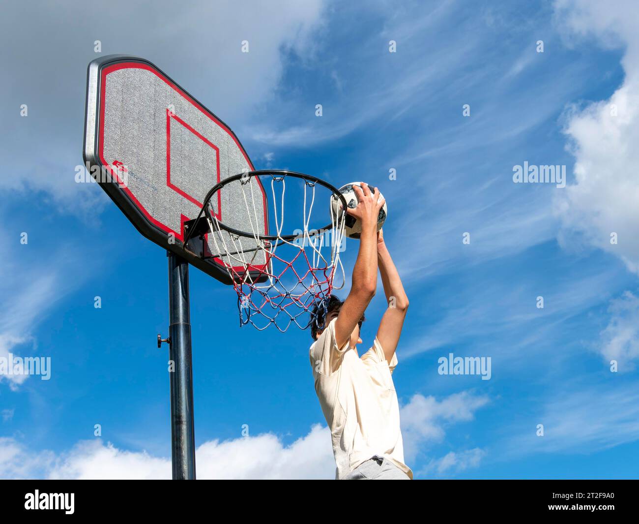 Basketball Jump with the ball to the basket and net, boy 14 years, sport activity with children, Germany Stock Photo