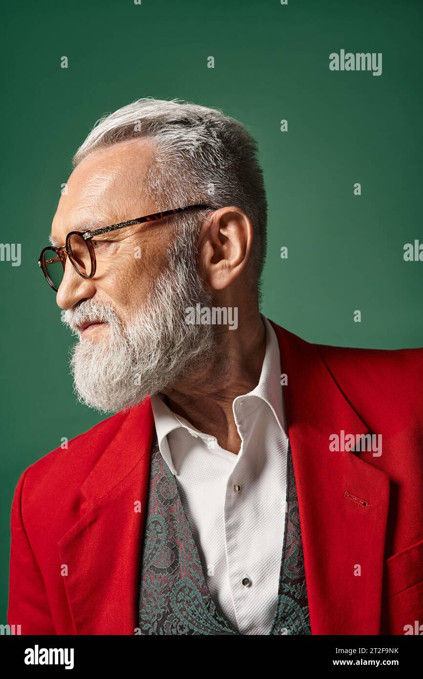 portrait of handsome classy Santa Claus posing in profile on dark green backdrop, winter concept Stock Photo